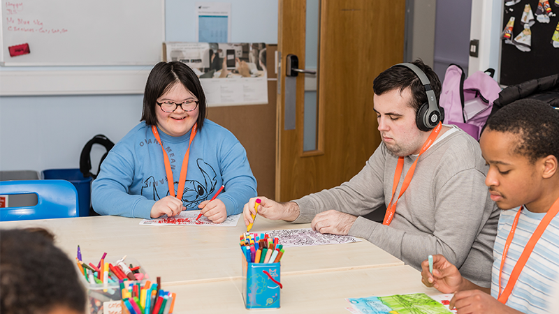 Three people colouring on a table