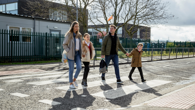 Family using a zebra crossing at a school