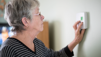 Image of an older person adjusting heating controls